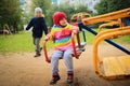 Children ride on the carousel in the playground. Playing children. Little cute babes ride on a swing. Royalty Free Stock Photo