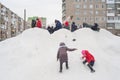 Children ride on a snow slide, parents keep order.