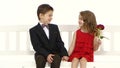 Children ride a swing and a little boy kisses the girl on the cheek. White background