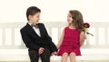 Children ride a swing and a little boy kisses the girl on the cheek. White background. Slow motion