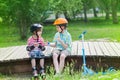 Children with rollers and scooter sit on a wooden platform