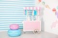 Children room with blue stripe background. candy stall photo zone with big macaroons, sweets and marshmallows. trolley with ice cr