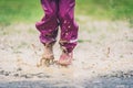 Children in rubber boots and rain clothes jumping puddle defocused. Royalty Free Stock Photo