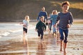 Children Run Ahead As  Multi-Generation Family Walk Along Shore On Winter Beach Vacation Royalty Free Stock Photo