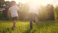 children run in the park. a boy and a girl holding hands run through the grass in the summer at sunset in the park Royalty Free Stock Photo