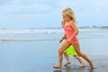 Children run with splashes by water pool along surf edge Royalty Free Stock Photo