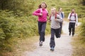 Children running ahead of parents, walking on a country path during a family camping trip, front view, close up