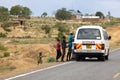 Children running towards a car on a Kenyan road, hoping for sweets from passing drivers