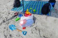 Children`s beach toys, sandals and knapsacks on beach sand near a multi-colored beach blanket Royalty Free Stock Photo