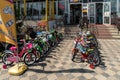 Childrens bicycles are displayed for sale and rent on the pavement in front of the store on a summer day