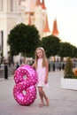 Children`s birthday. Smiling a beautiful blond little girl with a helium ball in the form of a figure eight celebrates her Royalty Free Stock Photo