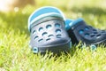 Children`s blue slippers on the green grass in the garden, shoes for children, beach fashion for kids, a concept of