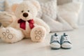 Children`s blue sneakers lie on the table against the background of pillows and soft toys . The concept of waiting for a newborn