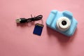 Children camera on a pink background. The camera is blue, the memory card and the cord. The camera is located in the middle. Royalty Free Stock Photo