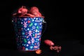 ChildrenÃ¢â¬â¢s Christmas bucket with ornaments filled with red potpourri on black background Royalty Free Stock Photo