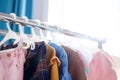 Pastel color children`s clothes in a Row on Open Hanger indoors. Clothes for little ladies hung in the children`s room