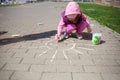 Children`s day. girl draws sun with chalk on sidewalk. kids walk outdoor. summer activity Royalty Free Stock Photo