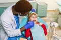 Children`s dentistry, Pediatric Dentistry. A male African-American stomatologist is treating teeth of a school-age girl