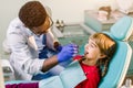 Children`s dentistry, Pediatric Dentistry. A male African-American stomatologist is treating teeth of a school-age girl