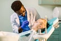 Children`s dentistry, Pediatric Dentistry. A male African-American stomatologist is treating teeth of a school-age boy