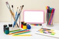 Children's digital tablet with a blank screen on a white table with multicolor drawing supplies.