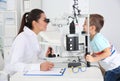 Children`s doctor examining little boy with ophthalmic equipment