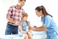 Children`s doctor vaccinating little girl near parent