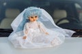 Children`s doll at a wedding. A doll in a wedding dress on the hood of a car Royalty Free Stock Photo