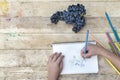 Children`s drawing, grapes and colored pencils. Wooden table. To