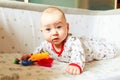 Children`s emotions. The child is in bed and playing with toys. A child at home knows the world. Baby learns to play Royalty Free Stock Photo