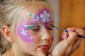 Children's face painting. The artist paints a princess crown on a small white blonde girl. Royalty Free Stock Photo