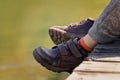 Children`s feet in brown leather shoes over the water. Royalty Free Stock Photo