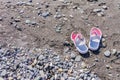 Children`s flip flops on the beach. Copy space. Tourism and vacation concept