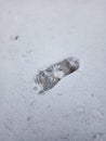 Children`s footprint from a boot on white snow in the winter season.