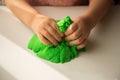 Children`s games. Sand. Child development. Close up of children`s hands playing with green kinetic sand on white table; selectiv Royalty Free Stock Photo