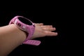 Children`s GPS watch. Pink smart watch on hand. Chidren`s hand with watch on black