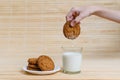 Children`s hand dries oatmeal cookies in a glass of milk.
