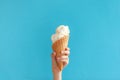 Children`s hand holds delicious vanilla ice cream cone on a blue background Royalty Free Stock Photo