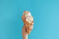 Children`s hand holds delicious vanilla ice cream cone on a blue background Royalty Free Stock Photo