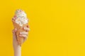 Children`s hand holds delicious vanilla ice cream cone on a bright yellow background Royalty Free Stock Photo