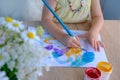 children's hand paints with brush, small child, little girl preschooler 3 years creates bright picture on paper