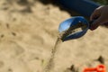 Children`s hand pours sand with a blue shovel Royalty Free Stock Photo