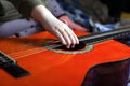 Children hand pulls the strings on an orange acoustic guitar Royalty Free Stock Photo