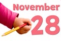 Children`s hand writes November 28 in red pencil. White background with autumn date, business and holiday concept