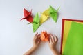 Children`s hands do origami from colored paper on white background. lesson of origami Royalty Free Stock Photo