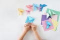 Children`s hands do origami from colored paper on white background. lesson of origami