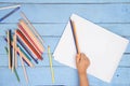 Children`s hands draw with pencils in the album on the blue table Royalty Free Stock Photo