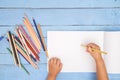 Children`s hands draw with pencils in the album on the blue table Royalty Free Stock Photo