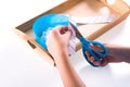 Children`s hands hold blue scissors and cut the paper. On a wooden tray are Montessori materials for a lesson Royalty Free Stock Photo