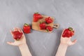 Children`s hands hold funny-shaped organic strawberries. Wooden serving board with bright ugly berries